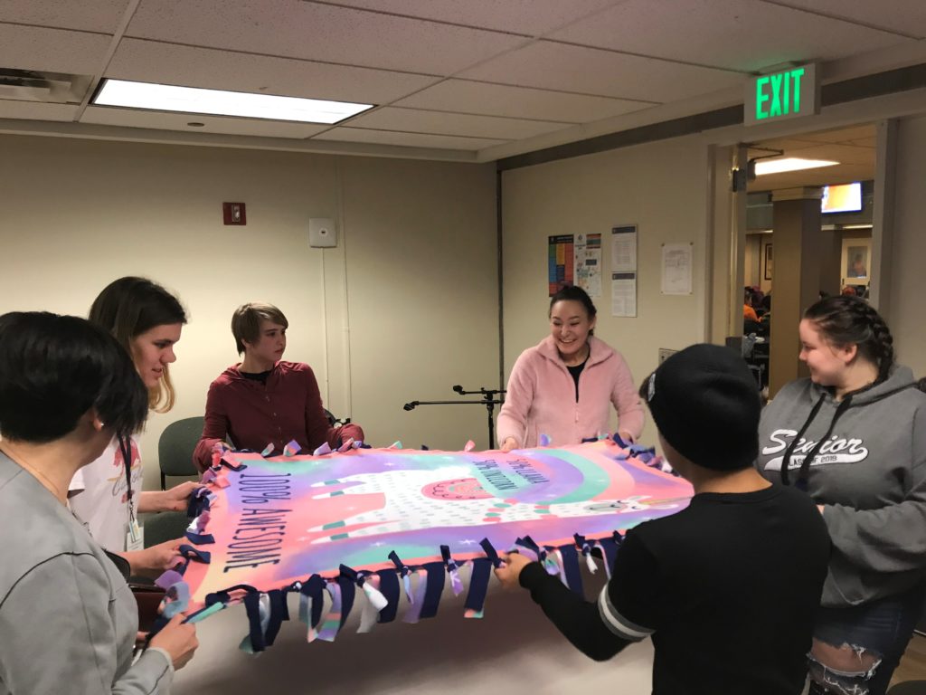 group of young adults pull corners of a blanket