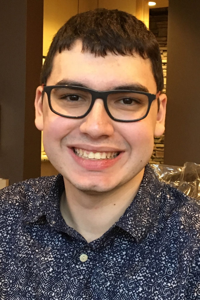 headshot portrait of a young man with short dark hair and glasses