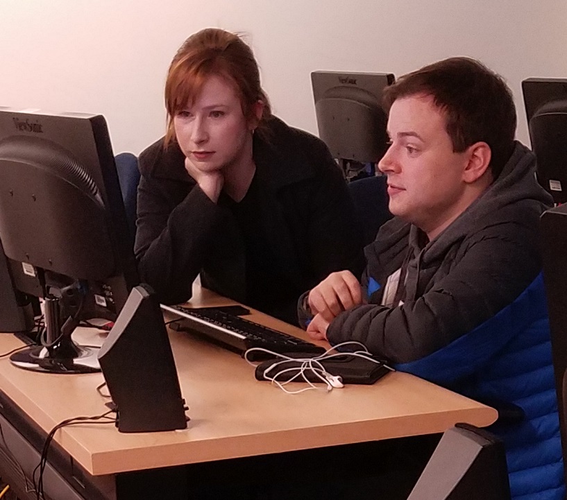 a woman and young man work at a computer together