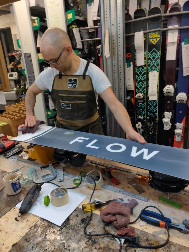 young man works on a snowboard 