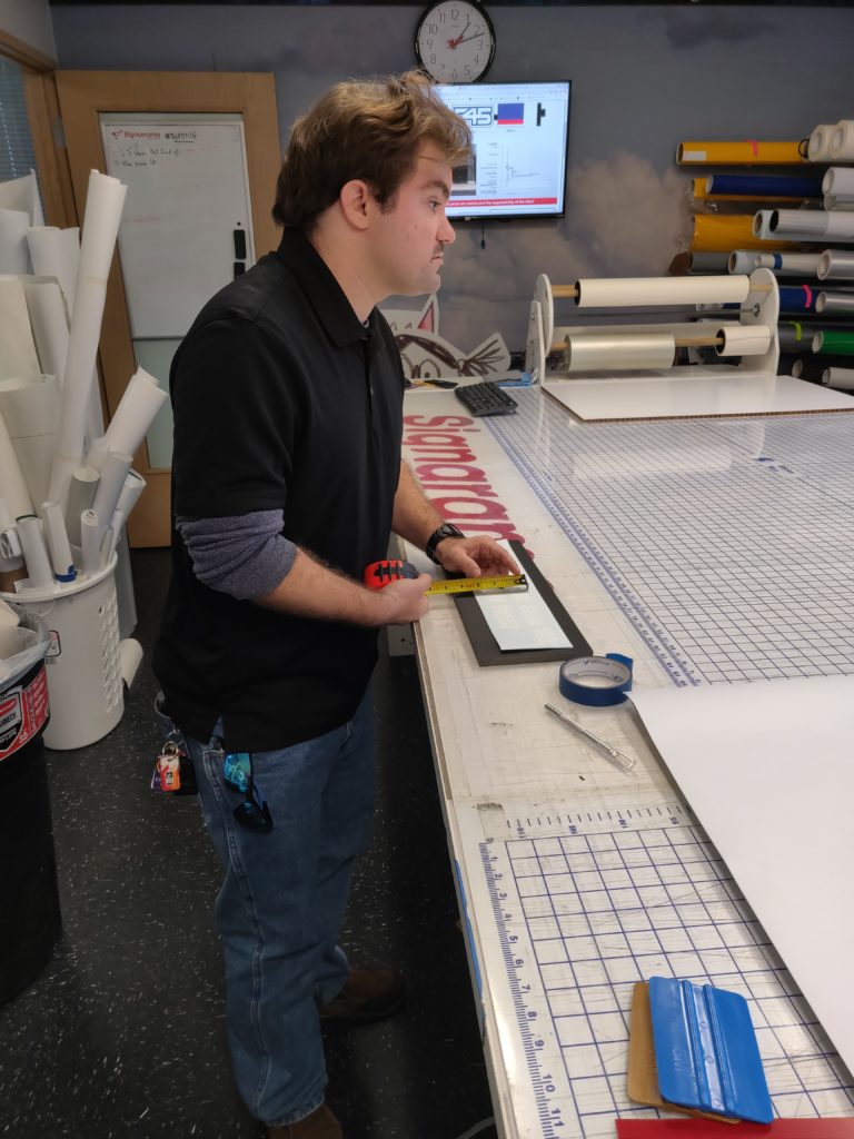 yougn adult man works on graphic sign at desk