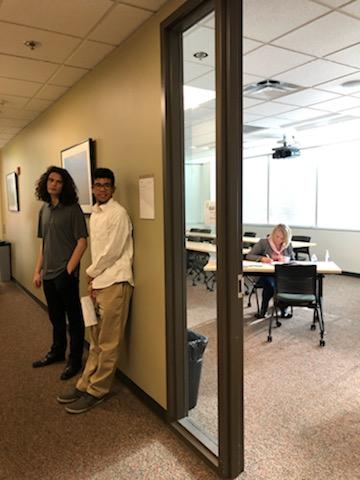 two young adults wait to interview outside a classroom