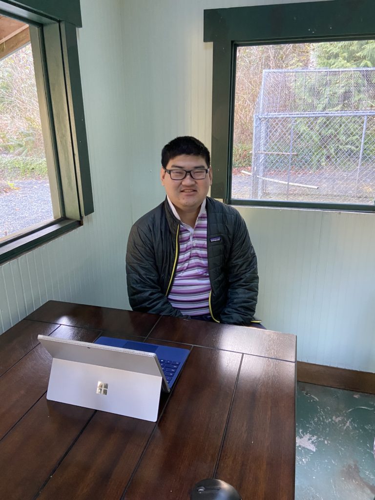 young adult male sitting at a desk with a laptop