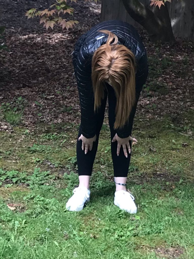 a young woman does yoga in her backyard