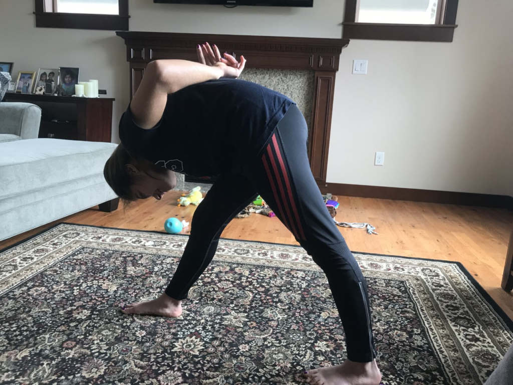 a young woman in yoga pyramid pose in her living room