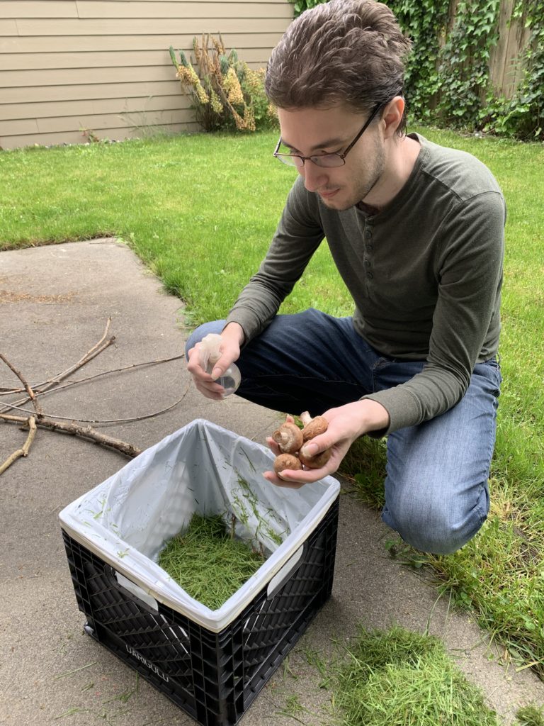 young man adds gress to small compost bin