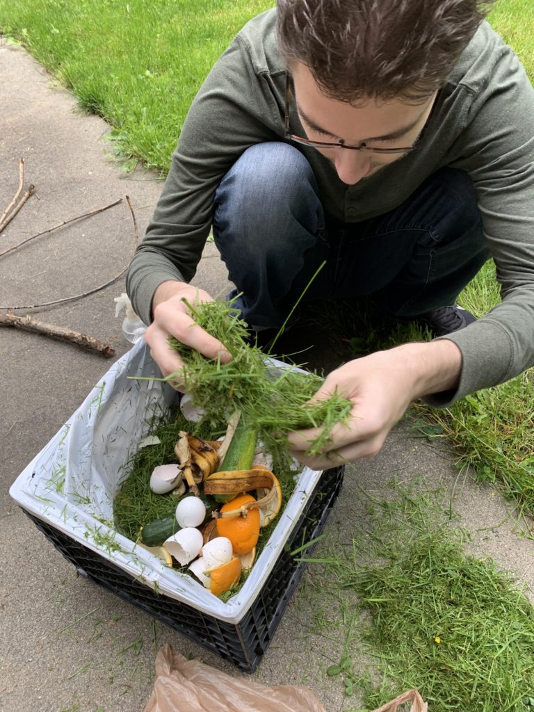 young man adds grass to mslal compost bin