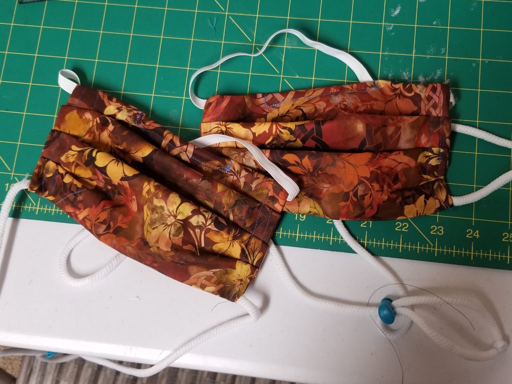 two colorful face masks on sewing table