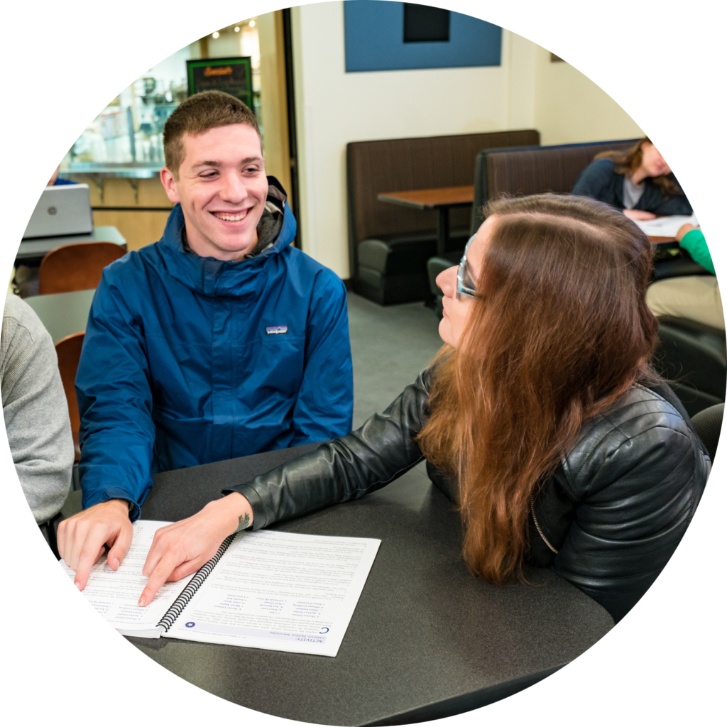 Two OLS students sit together at a table looking over papers together