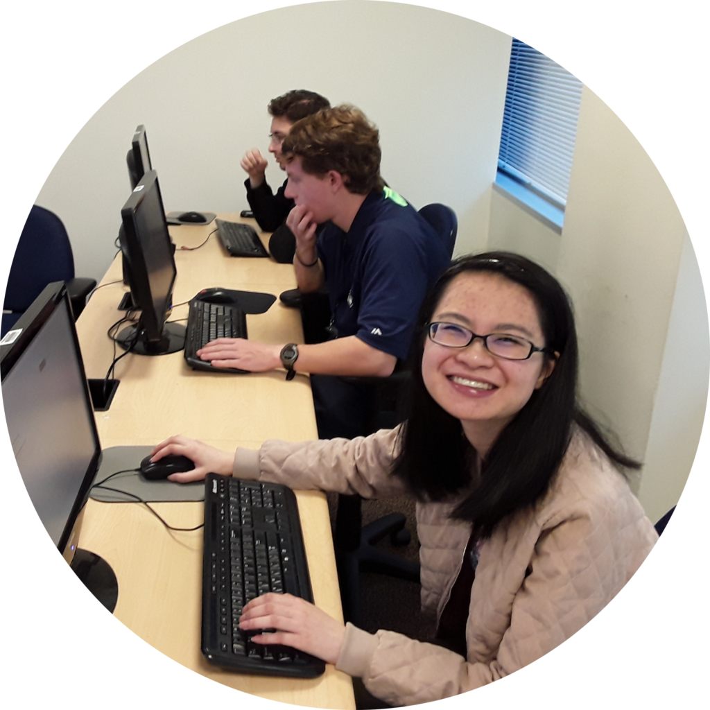 Three OLS students sit at computers working on classwork. 