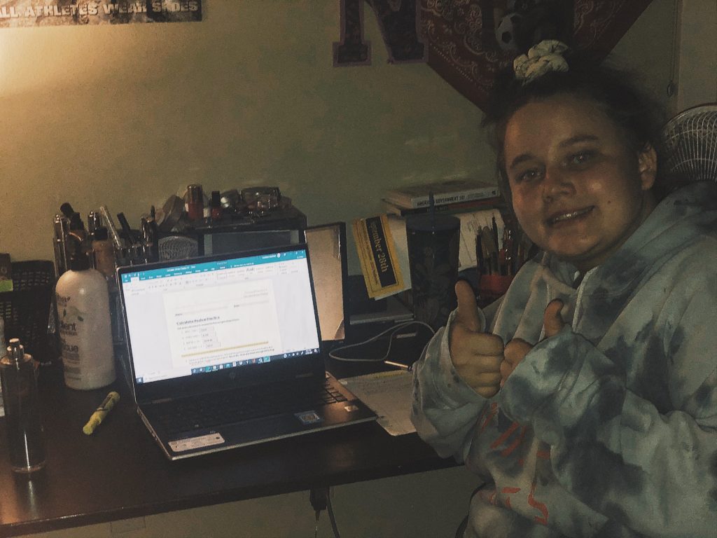 An OLS student poses for a photo in front of her laptop