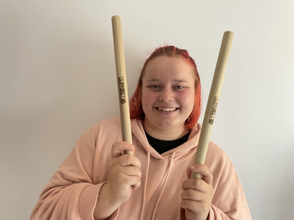 OLS Student holds up taiko bachi (taiko drum sticks).