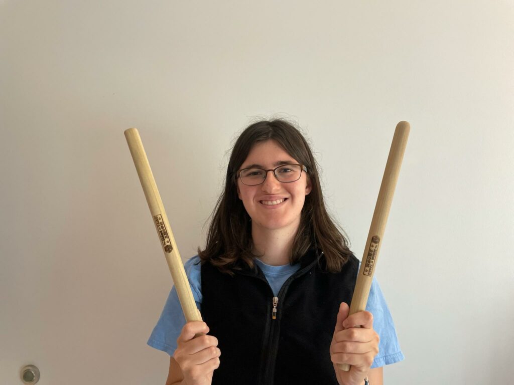 OLS Student Anna holds up taiko bachi (taiko drum sticks).