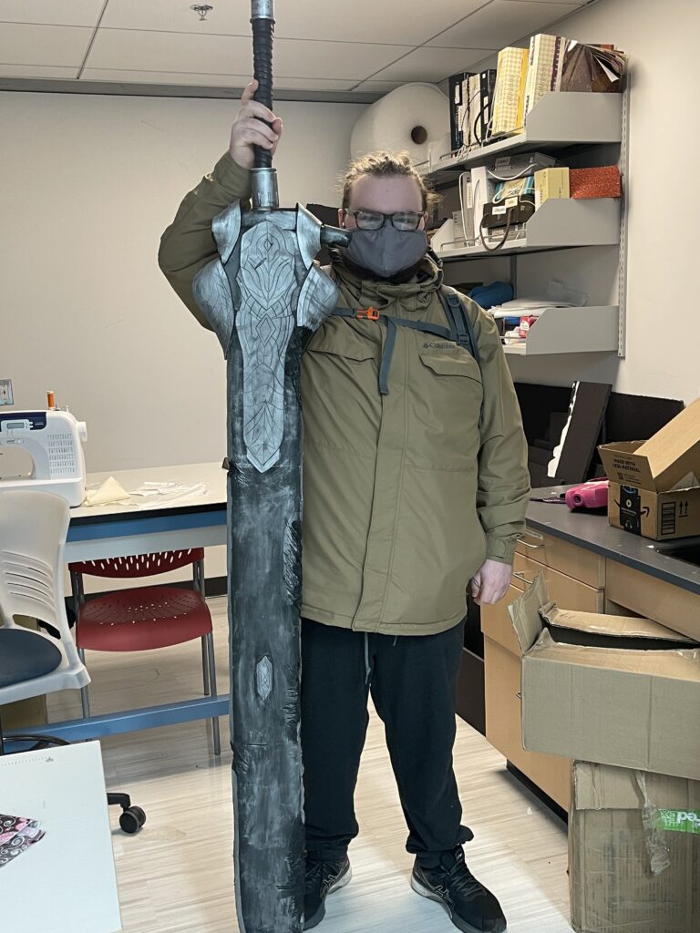 OLS Student holds up a large 3D printed sword. 