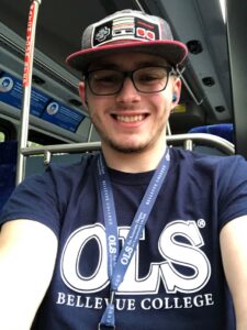 A young man wearing s baseball cap and an OLS bellevue College shirt on the bus