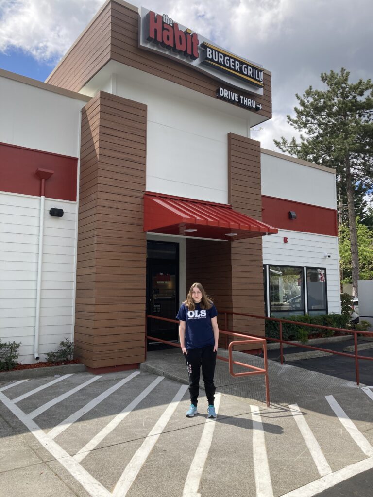 A young woman in an OLS tshirt outside a Habit burger restaurant