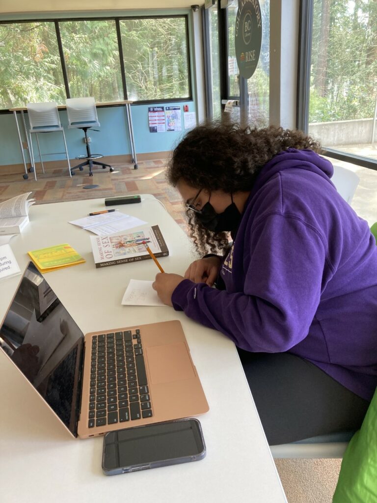 An OLS student works on their zine at a desk. 