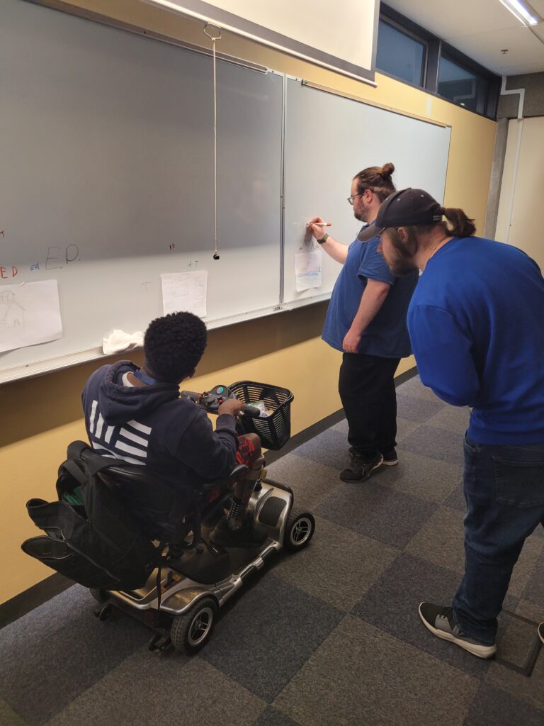 three OLS students working on a whiteboard in class