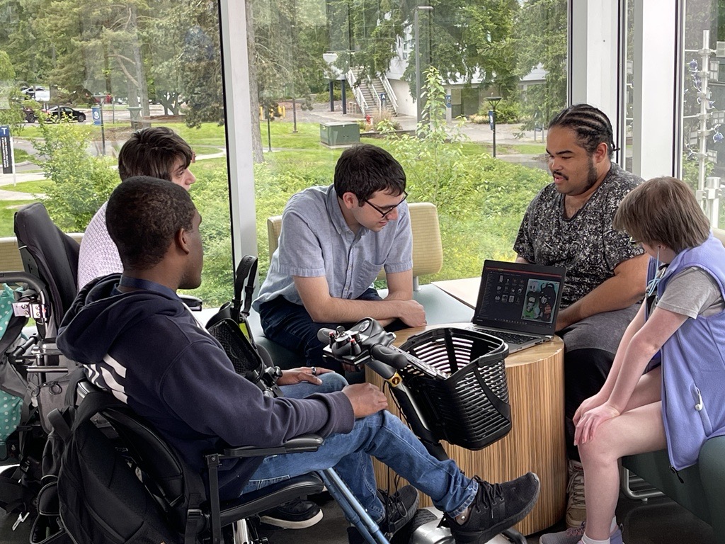 Five OLS Students sit together on campus working on a laptop