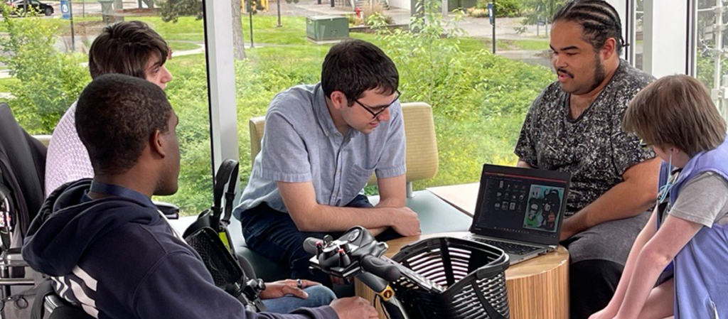 Five OLS Students sit together on campus working on a laptop