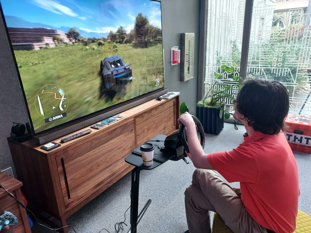 An OLS student plays a video game with an inclusive steering wheel controller