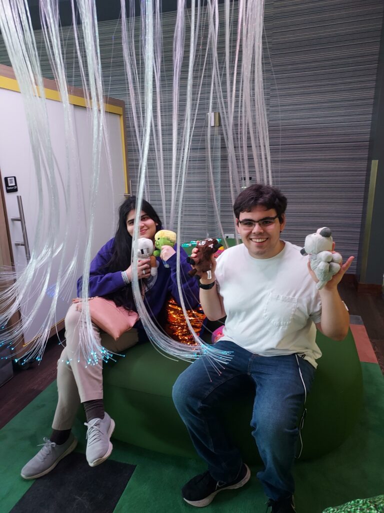 Two OLS students sit under a funky canopy on a green couch holding stuffed animals