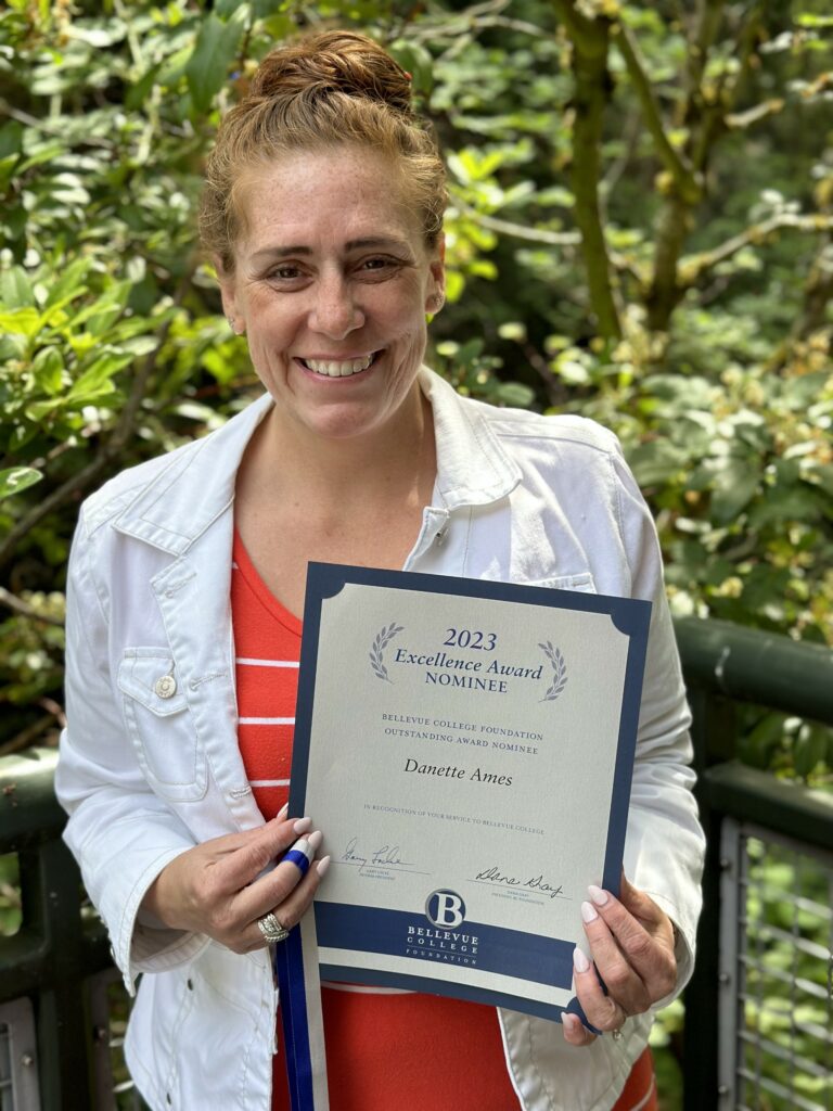 An OLS Faculty member smiles with her Excellence Award nomination certificate.