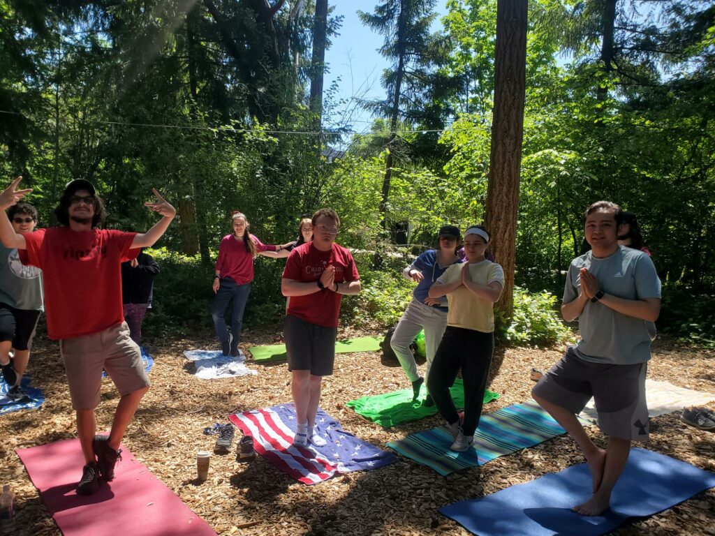 A group of OLS Bellevue College students practice Yoga in a forested area.