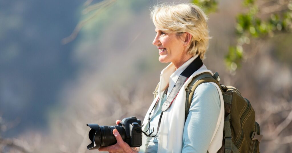 Female photographer holding digital camera on top of mountain