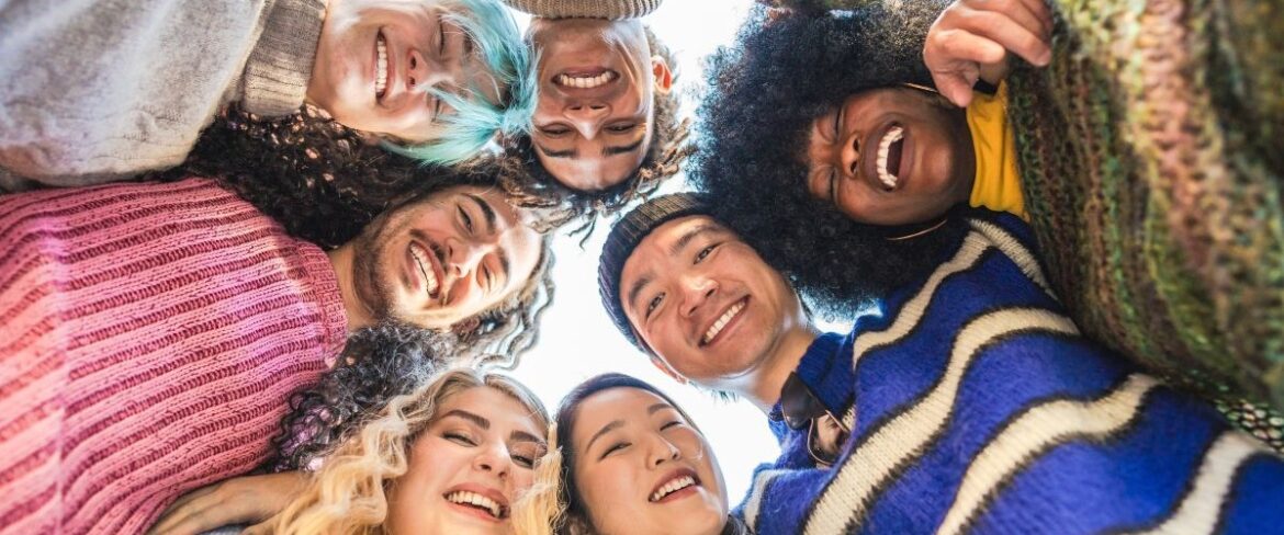 Group of adults looking down at a camera in a circle smiling