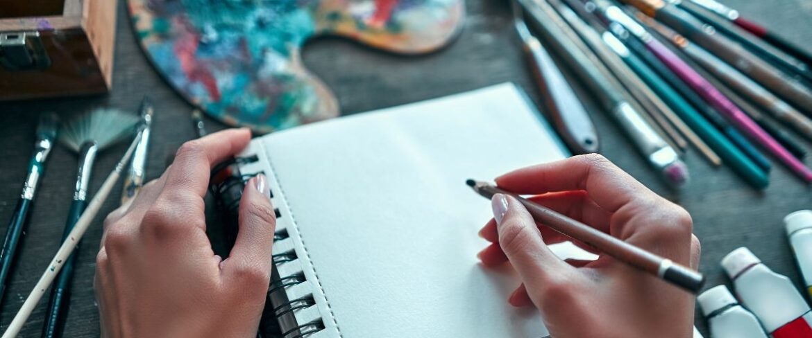 hands with paper and art supplies