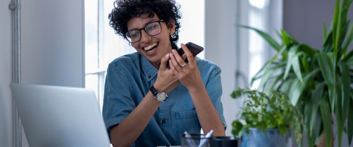 Woman laughing in front of a laptop