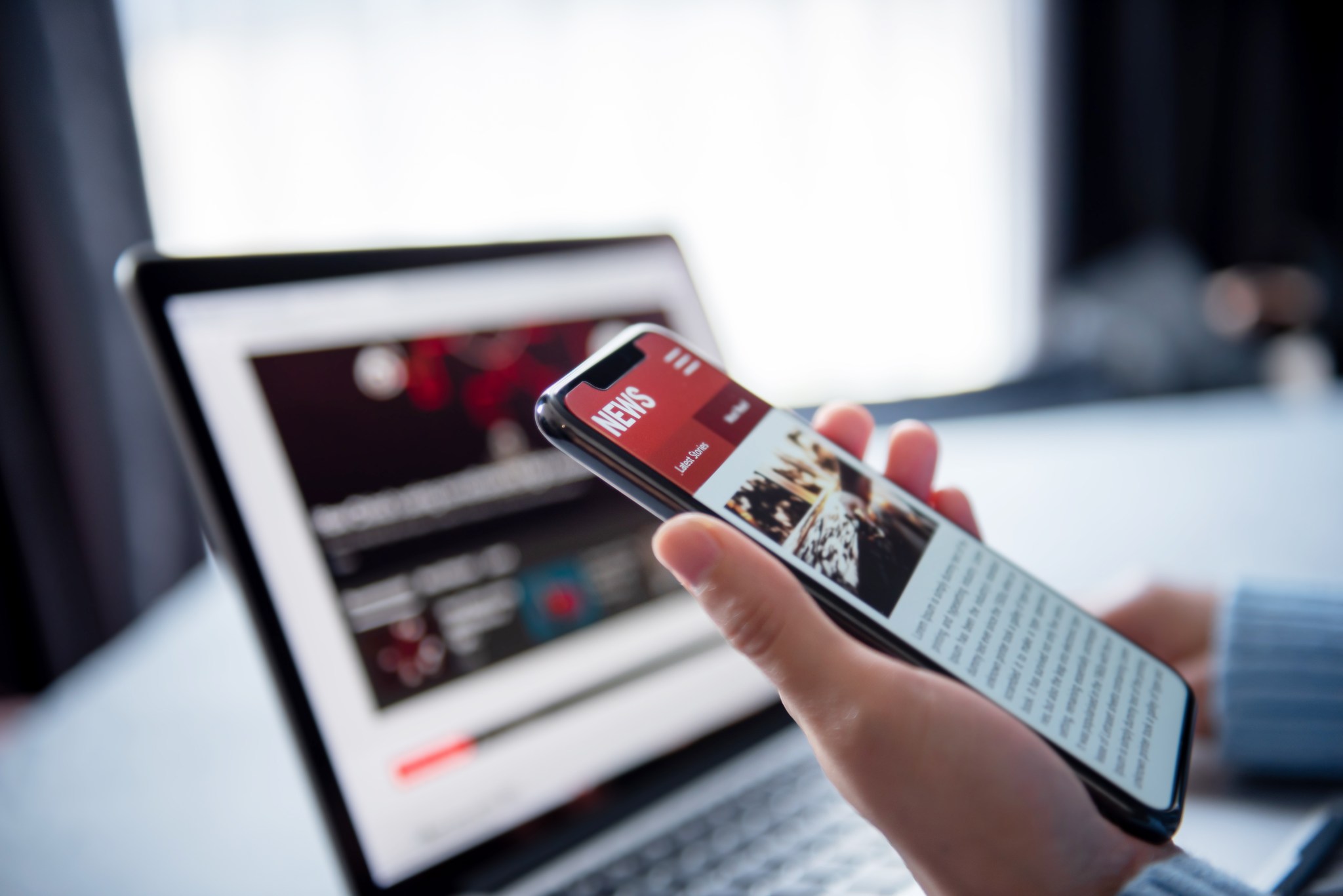 a computer and a mobile phone showing images of news