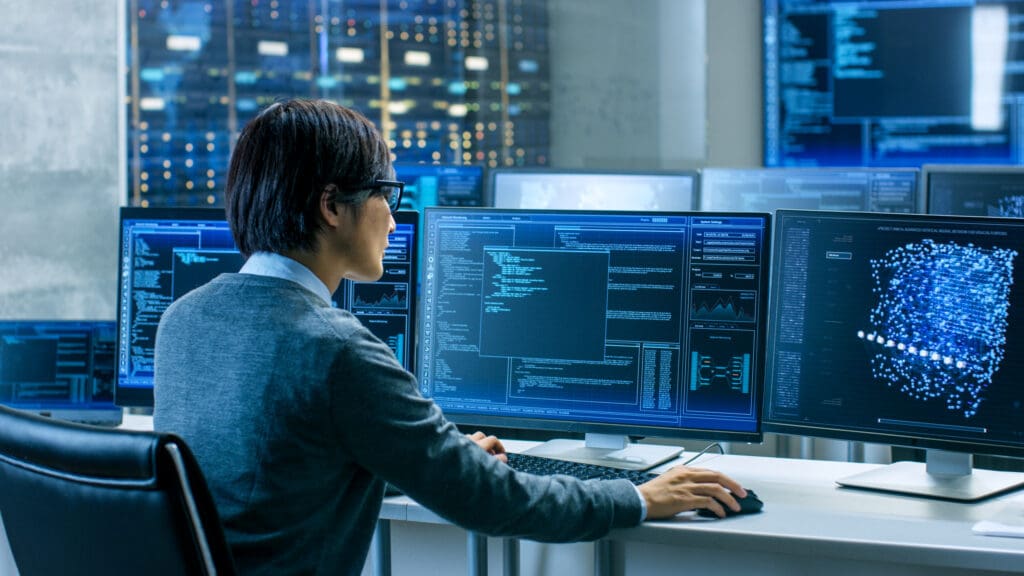 male sitting in front of computer screens
