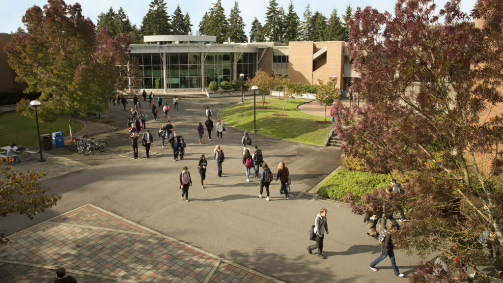 Students walking through Bellevue College courtyard in front of Student Union building on a sunny day.