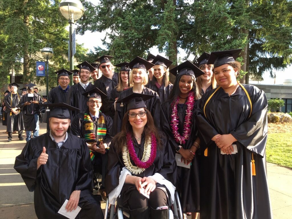 Diverse group of Bellevue College Occupational and Life Skills students wearing graduation caps and gowns at an outdoors commencement ceremony.