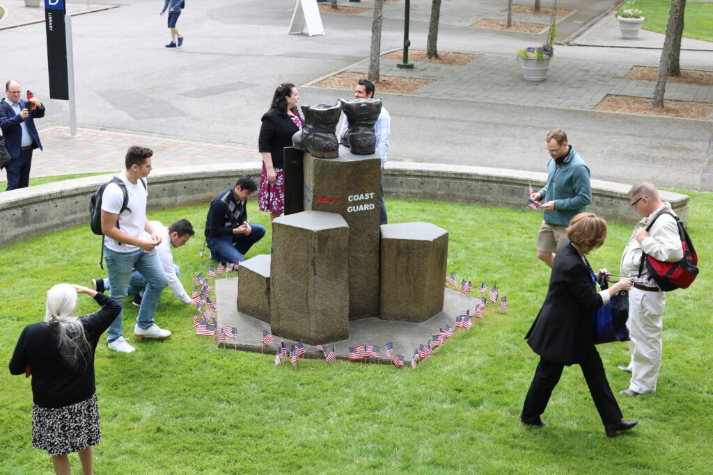 Students placing American flags around memorial sculpture for veterans on Bellevue College campus.