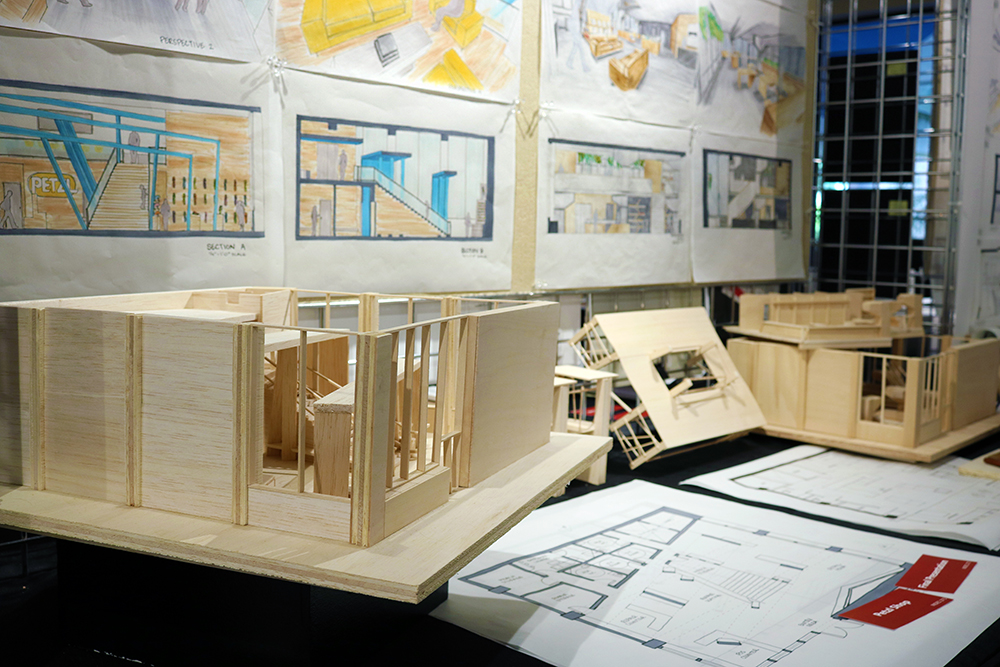 A display shows interior design drawings and a model of a building.