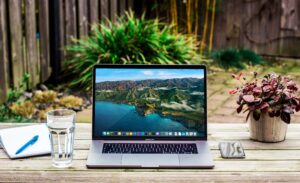 Patio table with laptop, pen, pad, water and plant