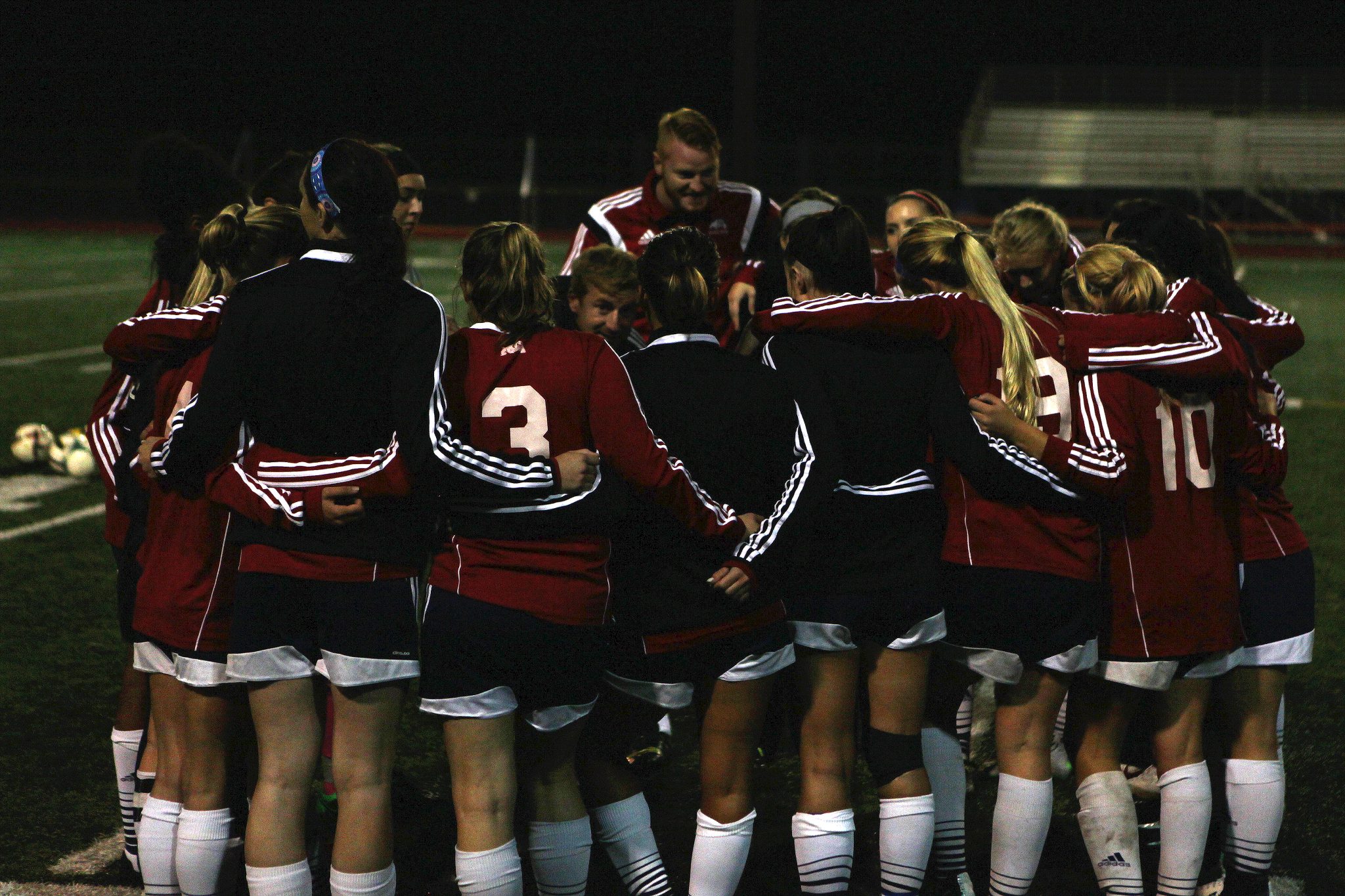 Belleve Colllege players and coaches huddle on the sideline after defeating Highline in a women's soccer match