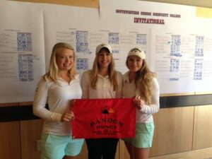 The BC women's golf team holding the SW Oregon Invite championship banner.