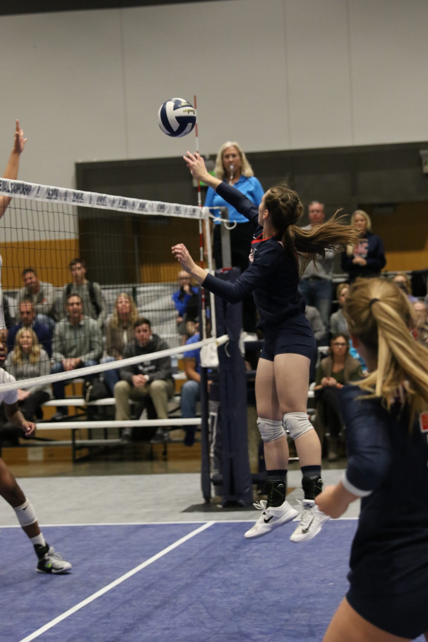 A BC player taps the ball over the net