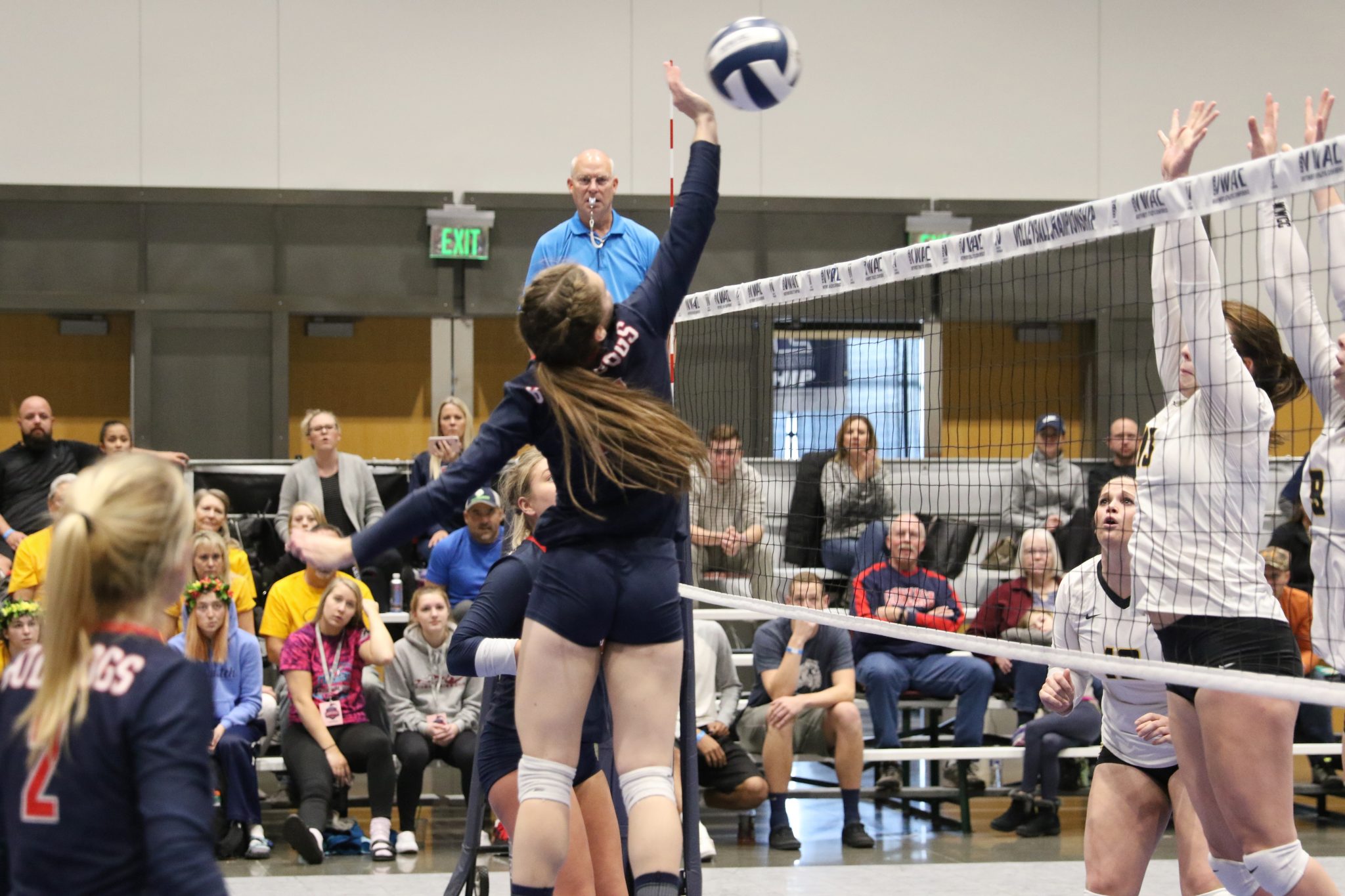 A BC player taps the ball over the net