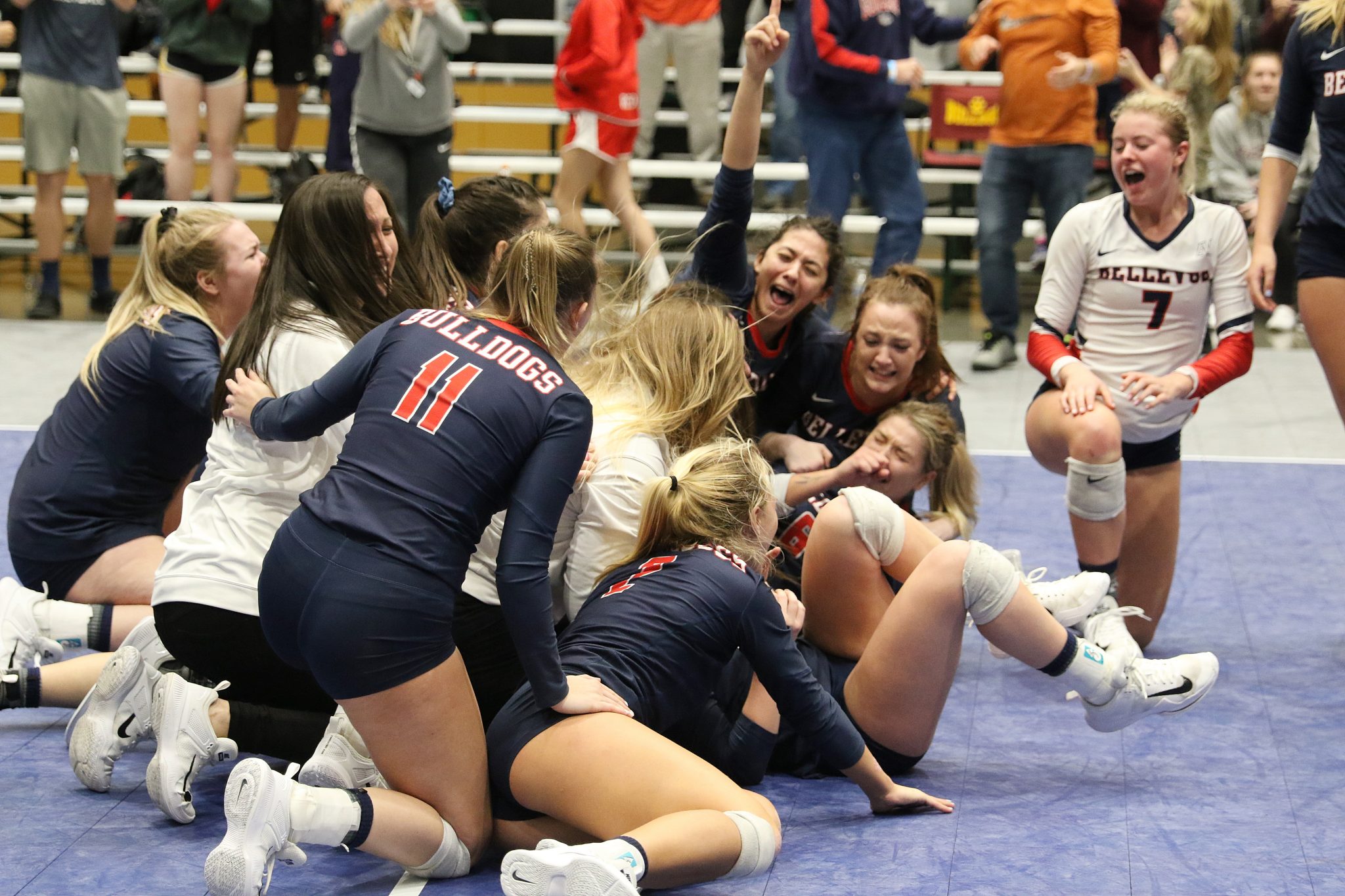 BC players and coaches in a pile on the floor to celebrate a hard-fought victory