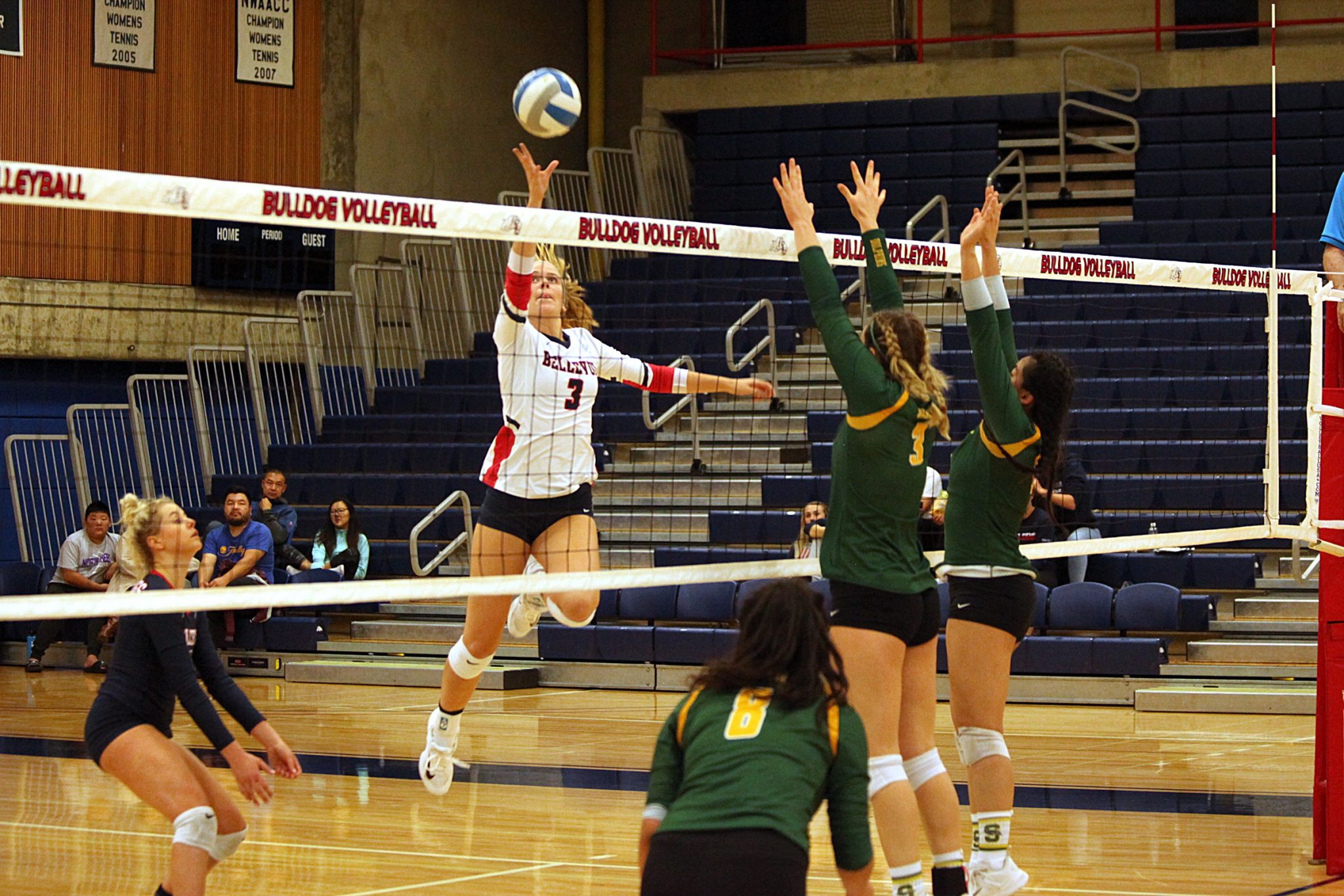 A BC player taps the ball at the net