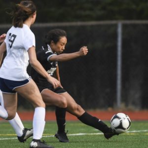 Juneau-Douglas’ Malia Miller, right, kicks a ball while defended by an opponent