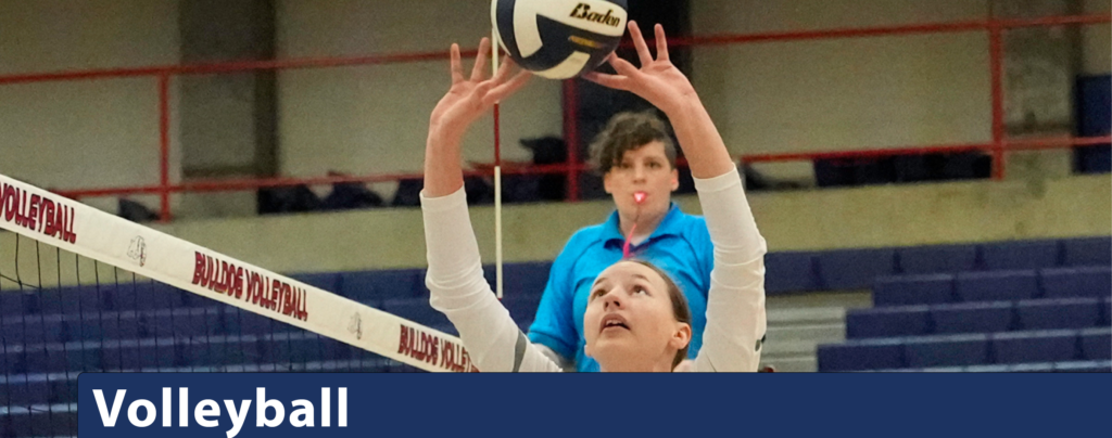 Player setting close to the net with referee looking on between her outstretched arms.