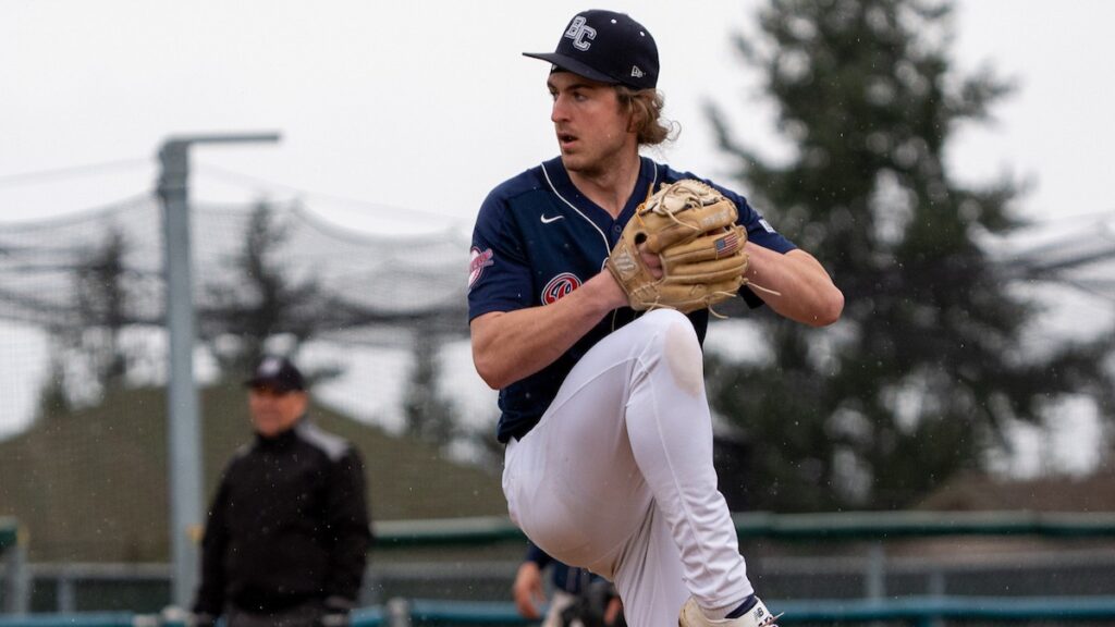 Baseball player winding up for the pitch, forward knee raised for the lunge.