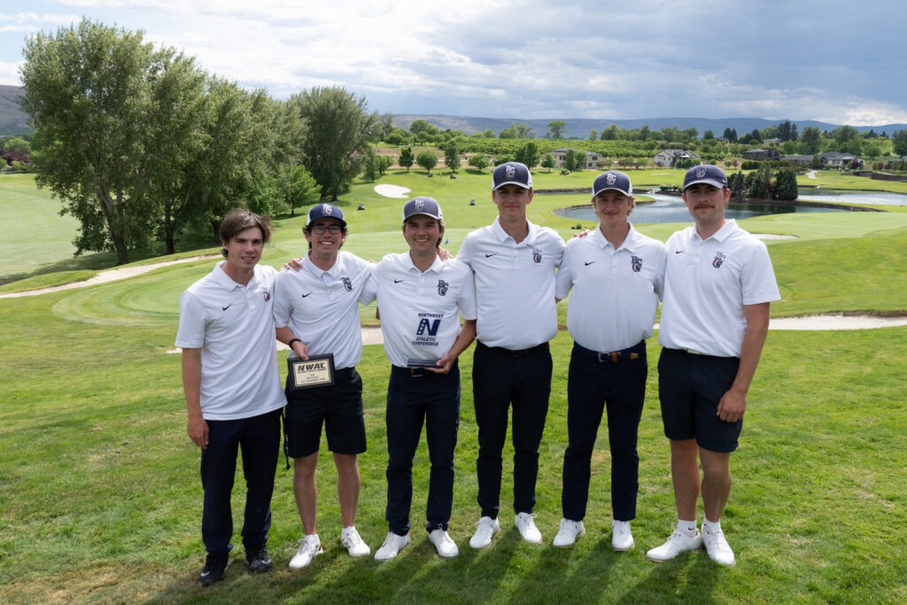 Men's golf team with a plaque on a lush green with an overcast sky and clouds in the distance.