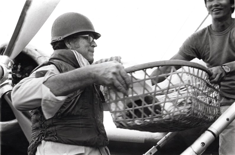 Photo of a Cambodian genocide escape with a male adult transporting a baby in a basket